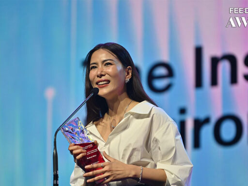 Cherry เข็มอัปสร ยืนรับรางวัล “Inspiration of the Year: Environmental Awareness” พร้อมแบ็คกราวด์ไอคอนสิ่งแวดล้อมและโลโก้ FEED x Khaosod